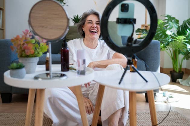 Joyful video creator laughing in home workspace with beauty products model released, Symbolfoto property released, ATSF00027