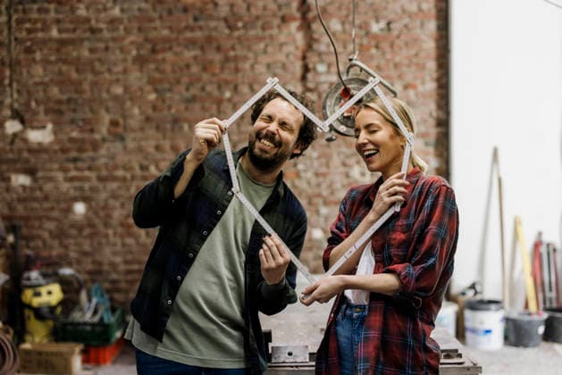Couple smiling and planning renovation with measuring tape at construction site model released, Symbolfoto property released, RAYF01280