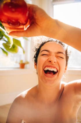 Woman joyfully laughing holding a red apple Somerville, Massachusetts, United States CR_FKNH251215-1903341-01 ,model released, Symbolfoto
