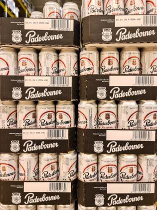 Kiel, Germany - 27. December 2025: Stapel von Paderborner Pilsener Bierdosen, die ein Supermarkt- oder Lagerregal füllen 1127162933