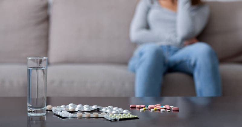 Suicide by medication overdose. Pills and water on table and depressed young woman crying on background, copy space Suicide by medication overdose concept. Heap of pills and glass of water on table and blurred young woman with depression crying on background, copy space. Selective focus, model released, , 97472298.jpg RECORD DATE NOT STATED