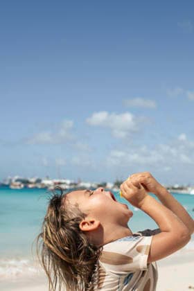 Boy squeezing lemon into mouth on sunny beach in caribbean Speightstown, Saint Peter, Barbados R_WDJM251226A-1917143-01 ,model released, Symbolfoto