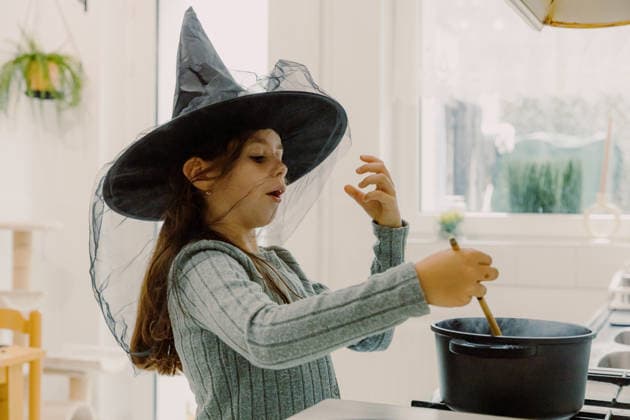 Cute girl in a witch hat cooks terrifying Halloween pasta Portrait of one beautiful Caucasian girl in a black witch hat with tulle, having emotional fun and cooking Halloween pasta, preparing a holiday treat, standing in the kitchen on an autumn day, close-up side view. Concept time to cook, holiday preparation, model released, , 97783508.jpg RECORD DATE NOT STATED