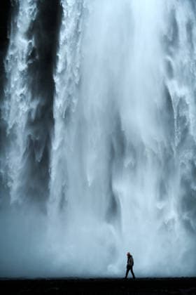 Hiker at Skogarfoss Silhouetted and Dawrfed by Massive Waterfall Vik, Mýrdalshreppur, Iceland CR_GASU260104-1929942-01 ,model released, Symbolfoto