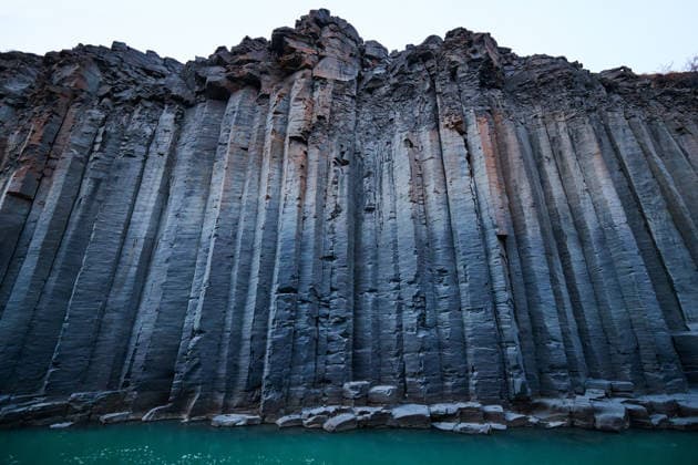 Creative Highlights World Hiker Dwarfed by Tall Walls in Studlagil Canyon Akureyri, Akureyrarbær, Iceland CR_GASU260104-1929957-01
