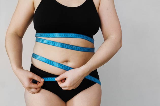 Eine Frau steht vor einem schlichten Hintergrund und misst ihre Taille mit einem blauen Maßband Eine Frau steht vor einem schlichten Hintergrund und misst ihre Taille mit einem blauen Maßband (License=RF) ,model released, Symbolfoto Copyright: xZoonar.com ElenaxNazarovax 24418934 ,model released, Symbolfoto ,property released