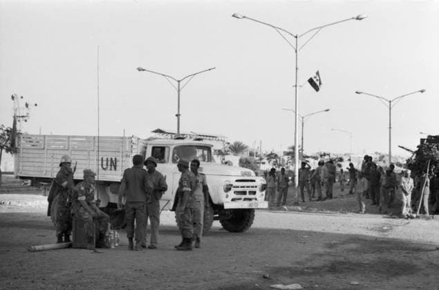 UN-Soldaten in Tarnuniform stehen und sitzen vor einem weißen UN-Lkw in einer Straßenkreuzung von Suez, 1973. Einige Soldaten tragen Helme, andere Baretts. Im Hintergrund sind ägyptische Soldaten und Zivilisten zu sehen, die sich an der Straßenseite versammelt haben. Über der Straße weht an einem Laternenmast eine UN-Flagge während des Jom-Kippur-Kriegs. Suez as-Suwais Ägypten *** UN Soldiers in Camouflage uniform Standing and sit before a white UN TRUCK in a Crossing from Suez, 1973 some Soldiers carry Helmets, other Berets at Background are Egyptian Soldiers and Civilians to see, the itself to the Street side gathered have via the Street blows to a lamppost a UN Flag during of Jom KIPPUR War Suez As Suwais Egypt Copyright: xUnitedxArchivesx xSvenxSimonxArchives SVS_94010002482