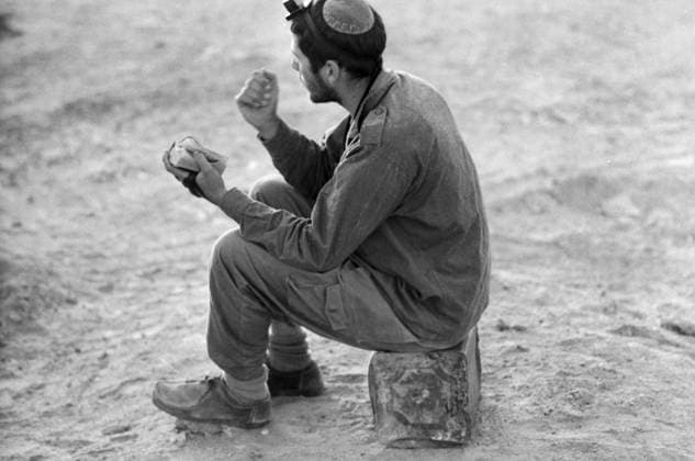Ein israelischer Soldat sitzt auf einem improvisierten Sitz aus einem Kanister in der Wüste Sinai und betet. Er trägt eine Kippa und Gebetsriemen (Tefillin) und hält ein Gebetbuch in den Händen. Aufnahme aus der Zeit des Jom-Kippur-Krieges, 1973. Wüste Sinai Ägypten *** a Israeli Soldier sits at a improvised Seat from a Canister in the Desert Sinai and pray he carries a Kippa and Prayer Strap Tefillin and holds a Prayer book in the Hands Recording from the Time of Jom KIPPUR war, 1973 Desert Sinai Egypt Copyright: xUnitedxArchivesx xSvenxSimonxArchives SVS_94010002630