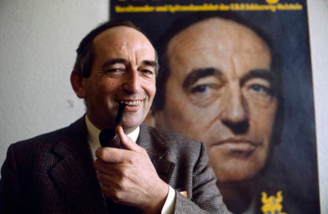 Uwe Ronneburger mit Pfeife in der Hand und lächelndem Gesichtsausdruck vor einem großformatigen FDP-Wahlplakat mit seinem Porträt. Parteipolitisches Umfeld mit eindeutigem Bezug zur Freien Demokratischen Partei, Deutschland, 1970er. *** Uwe Ronneburger with Whistle in the Hand and lächelndem Facial expression before a large format FDP Election poster with his Portrait Party politics Environment with clear Reference to Free Democratic Party, Germany, 1970s Copyright: xUnitedxArchivesx xSvenxSimonxArchives SVS_94040000466