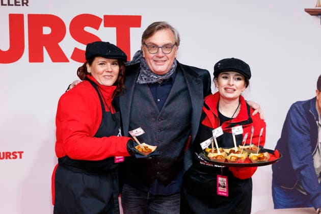 Entertainer Hape Kerkeling mit zwei Damen, die Bratwurst an Premierengäste verteilen, bei der Weltpremiere des Films Extrawurst im Lichtburg Kino in Essen. Essen, 07.01.2026 NRW Deutschland Copyright: xChristophxHardtx