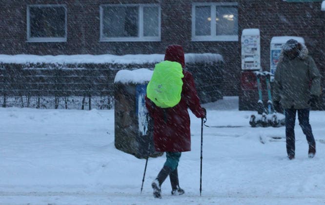 Schneetreiben am Donnerstagmorgen in Hamburg. Eine Frau geht mit Skistöckern über eine mit Schnee bedeckte Straße. Winterhude Hamburg