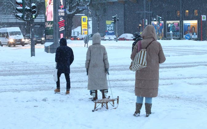 Schneetreiben am Donnerstagmorgen in Hamburg. Passanten stehen an einer Fußgängerampel. Die Straße ist mit Schnee bedeckt. Winterhude Hamburg