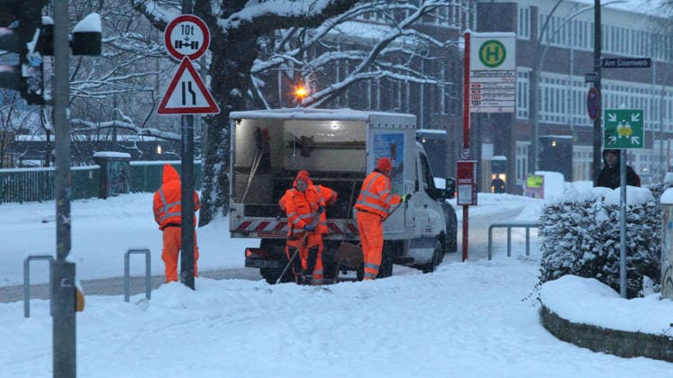 Schneetreiben am Donnerstagmorgen in Hamburg. Mitarbeiter vom Winterdienst räumen die Bushaltestelle Saarlandstraße mit Schneeschaufeln frei. Barmbek Hamburg
