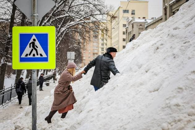 Russia. Moscow. A huge mountain of snow on Miusskaya Street, brought from the nearby areas of Moscow after the snow cyclone Frances in Moscow. People are moving to another part of the street on a snowy mountain RomanxNaumov