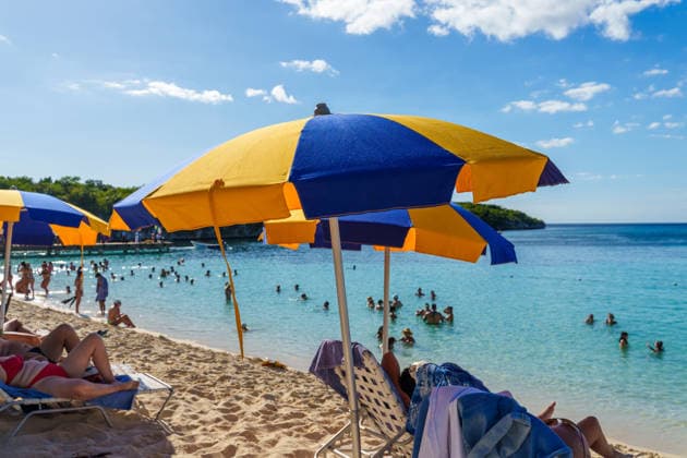 Isla Catalina, Dominican Republic, Caribbean - December 29, 2025: Vacationers lie in the shade under colorful parasols, while others swim in the clear sea and sunbathe. The scene depicts a typical summer vacation at the beach with relaxation, cooling off, and a sunny holiday atmosphere. *** Unter bunten Sonnenschirmen liegen Urlauber im Schatten, während andere im klaren Meer baden und sich sonnen. Die Szene zeigt den typischen Sommerurlaub am Strand mit Erholung, Abkühlung und sonniger Ferienstimmung.
