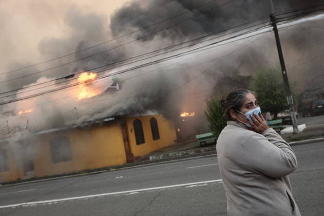 (260118) -- SANTIAGO, Jan. 18, 2026 -- A woman stands in front of a building affected by a forest fire in Penco, Biobio region, Chile, Jan. 18, 2026. Chilean President Gabriel Boric announced a state of catastrophe in the regions of Nuble and Biobio on Sunday after forest fires killed at least 16 people. Given the serious fires currently underway, I have decided to declare a state of catastrophe in the regions of Nuble and Biobio. All resources are available, Boric said in a post on social media X. (SpotNews) CHILE-BIOBIO-FOREST FIRES ZhuxYubo 