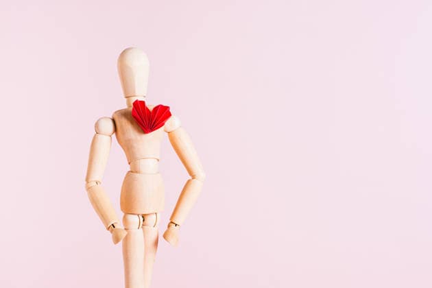 Holzmann mit einem roten Origami-Herz auf der Brust vor rosa Hintergrund Wooden man with a red origami heart on his chest on a pink background (License=RF) Copyright: xZoonar.com ElenaxRuix 24492940