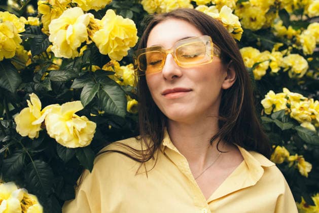 Junge Frau mit langen braunen Haaren und gelber Sonnenbrille posiert inmitten leuchtend gelber Blumen und schafft so eine fröhliche und lebendige Atmosphäre in einer natürlichen Umgebung. Female model with brown hair, wearing yellow sunglasses, stands amidst blooming yellow flowers, exuding a joyful and vibrant mood in a sunny environment (License=RF) ,model released, Symbolfoto Copyright: xZoonar.com DashaxPetrenkox 24497328 ,model released, Symbolfoto ,property released