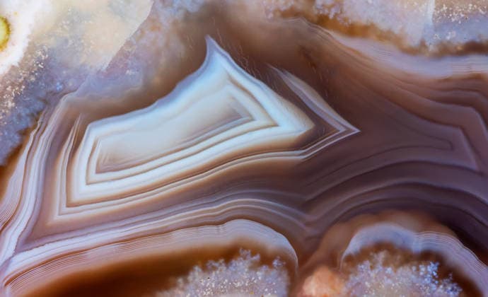 Eine Nahaufnahme der Makrostruktur eines grauen Achatminerals, die seine natürlichen Schichtmuster und kristallinen Details zeigt. A close-up macro texture of a grey agate mineral, showing its natural layered patterns and crystalline details (License=RF) Copyright: xZoonar.com gutaperx 24502474