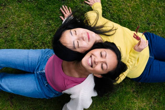 Happy women relaxing together on grass in a park model released, Symbolfoto, AMWF03552