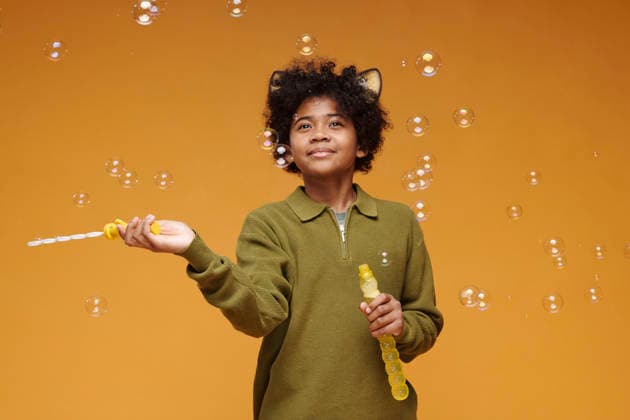 Kid with cat ear headband playing with soap bubbles in studio model released, Symbolfoto, DSHF02533