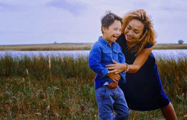 Mother and boy with Down syndrome laughing together outdoors in nature model released, Symbolfoto, AZF01100