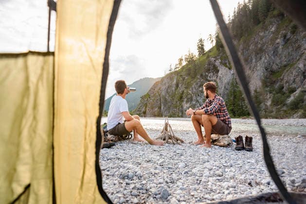 Brothers relaxing by riverside campfire during summer hiking adventure model released, Symbolfoto, DIGF26327