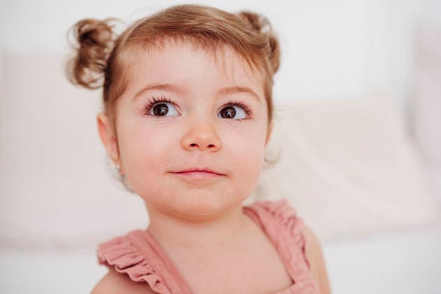 Smiling toddler with hair buns indoors showing innocence and curiosity model released, Symbolfoto property released, EBBF09267