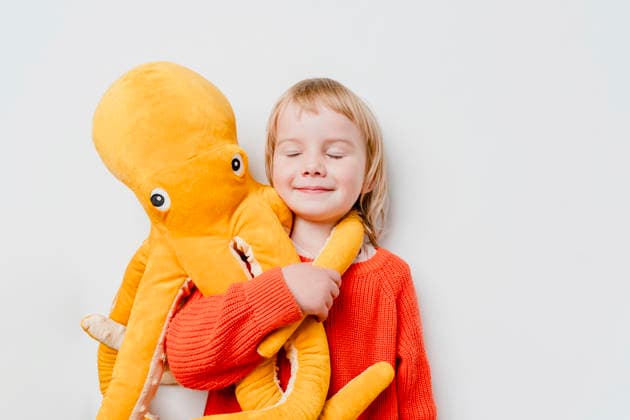 Smiling child hugging plush octopus toy in red sweater indoors model released, Symbolfoto property released, NDEF03161
