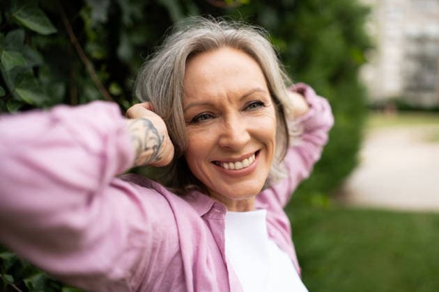 Smiling woman relaxing outdoors in a green park model released, Symbolfoto property released, OGSF00293