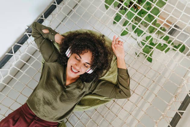 Businesswoman relaxing with headphones in a hammock at modern office model released, Symbolfoto property released, YTF03970