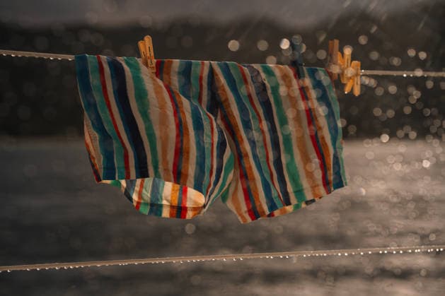 IMAGO Creative, Jahreszeit Sommer, Regen, Sommerregen Striped Men?s Swim Shorts Hanging on Catamaran Rail in Rain Victoria, Mont Fleuri, Seychelles CR_NMDM260127-1951716-01