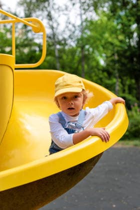A little boy riding on a yellow slide at a playground CR_YEPI260127-1951448-01 ,model released, Symbolfoto