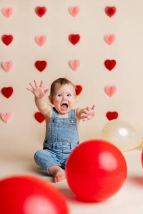 Baby in denim overalls with red hearts and balloons on Valentine set Concordia, Kansas, United States CR_ZMDZ260126-1950190-01 ,model released, Symbolfoto