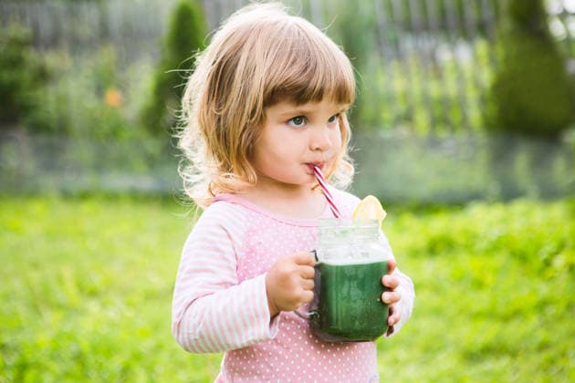 Jam Girl Summer. Süßes kleines Kind trinkt einen gesunden grünen Smoothie mit Strohhalm aus einem Glasbecher vor dem Hintergrund von Grünpflanzen im Freien. Jam Girl Summer. Cute little child drinks healthy green smoothie with straw in a jar mug against the background of greenery outdoor. (License=RF) ,model released, Symbolfoto Copyright: xZoonar.com UliaxZotaninax 24545419 ,model released, Symbolfoto ,property released