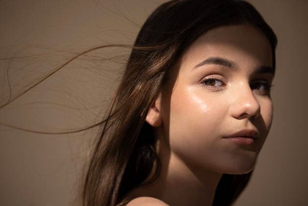 Eine junge Frau mit langen Haaren, beleuchtet von sanftem Licht, blickt über ihre Schulter und fängt einen Moment ruhiger Schönheit und Eleganz in einer minimalistischen Umgebung ein. Young woman with flowing hair is captured in soft light, gazing over her shoulder, showcasing natural beauty and elegance in a tranquil atmosphere (License=RF) ,model released, Symbolfoto Copyright: xZoonar.com DashaxPetrenkox 24547044 ,model released, Symbolfoto ,property released
