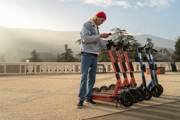 Junger Tourist versucht, einen E-Scooter mit einer mobilen App zu entsperren, um die Stadt mit einem Elektroroller zu erkunden. Young man tourist trying to unlock e-scooter with mobile app, exploring European city on e-bike. Caucasian millenial guy standing against amazing mountain view renting an electric scooter (License=RF) ,model released, Symbolfoto Copyright: xZoonar.com DmitriixMarchenkox xEnvatox 24552490 ,model released, Symbolfoto ,property released