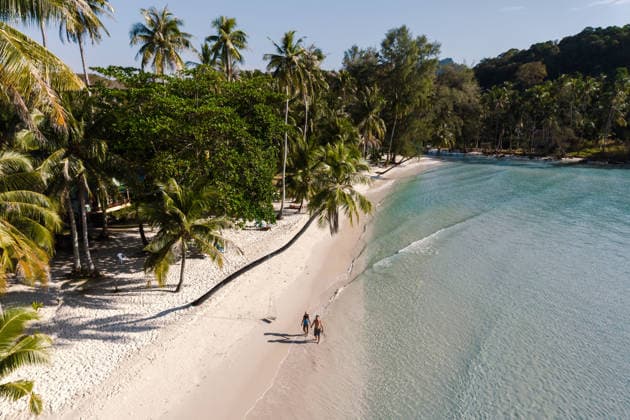 Gemeinsam spazieren gehen entlang der ruhigen Küste des Khlong Hin Beach auf Koh Kood in Thailand A couple walks hand in hand on the soft sandy beach of Khlong Hin, surrounded by lush palm trees and crystal-clear waters in beautiful Koh Kood, Thailand. (License=RF) ,model released, Symbolfoto Copyright: xZoonar.com FokkexBaarssenx 24580750 ,model released, Symbolfoto ,property released