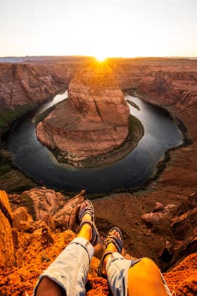 Dangling feet over Horseshoe Bend cliff at sunset Page, Arizona, United States CR_WLCB260128A-1952872-01 ,model released, Symbolfoto