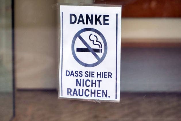 Rauchverbot in einem Gebäude, freundlicher Hinweis auf einem Schild an der Eingangstür *** Smoking ban in a Building, Friendly Note at a Shield to the Front door 1131607806