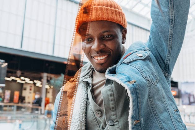 Junge Fotografin untersucht Filmstreifen, lächelnd in einem Einkaufszentrum, trägt orangefarbene Mütze, Jeansjacke, mehrschichtige Freizeitkleidung Young photographer looking at a film strip and smiling while standing in a shopping mall, wearing an orange beanie, denim jacket and layered clothing (License=RF) ,model released, Symbolfoto Copyright: xZoonar.com ElenaxShishkinax 23250596 ,model released, Symbolfoto ,property released