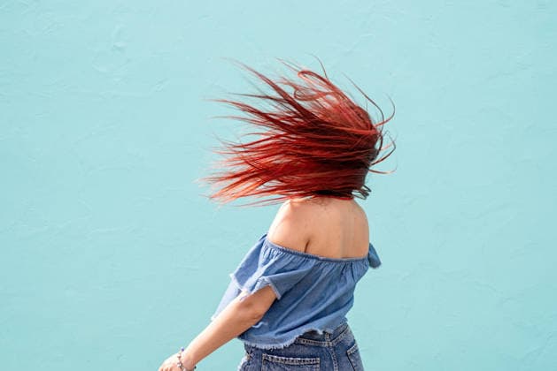 Fröhliche, trendige Frau mit roten Haaren tanzt vor blauem Wandhintergrund auf der Straße. Attractive young woman in summer clothes and sunglasses, dancing on blue wall background at street (License=RF) ,model released, Symbolfoto Copyright: xZoonar.com IlonaxShorokhovax 24608586 ,model released, Symbolfoto ,property released
