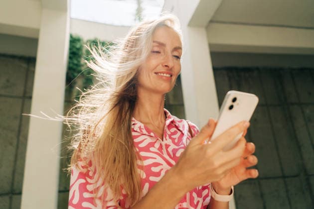 Porträt einer schönen modernen Frau, die auf einer Straße in der Stadt steht und ihr Mobiltelefon benutzt. Portrait of a beautiful modern woman using a mobile phone while standing on the street in the city. Long blonde hair flutters in the wind. (License=RF) ,model released, Symbolfoto Copyright: xZoonar.com TITOVAxILONAx 24612069 ,model released, Symbolfoto ,property released