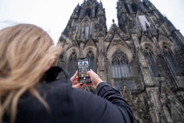 Touristin fotografiert den Kölner Dom mit einem Smartphone vor der Kathedrale in Köln, Deutschland. Tourist taking a photo of Cologne Cathedral with a smartphone in Cologne, Germany. *** Tourist taking a photo of Cologne Cathedral with a smartphone in front of the cathedral in Cologne, Germany Tourist taking a photo of Cologne Cathedral with a smartphone in Cologne, Germany Copyright: MarcoxBader