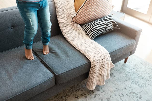 Home, legs and kid on sofa, jumping and playing with fun for development, break and tiptoe. Apartment, child growth and boy with adhd on couch, activity and naughty in afternoon, energy and game. model released property released Copyright: xx