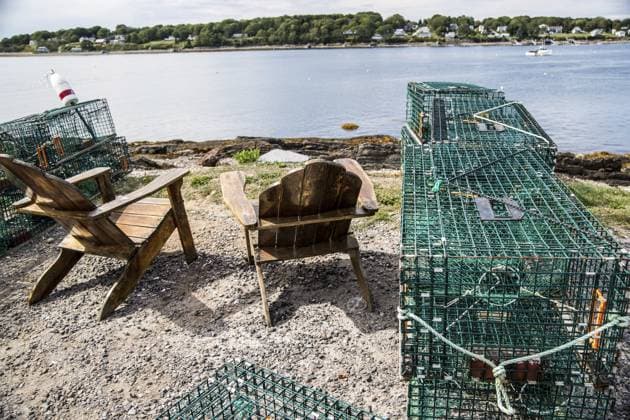 Zwei Adirondak Stühle, umgeben von Hummerfallen aus Draht, mit Blick auf einen Hafen von Maine Two Adirondak chairs surrounded by wire lobster traps overlooking a Maine harbor Copyright: imageBROKER JamesxF.xMattil ibxiqx16000703.jpg