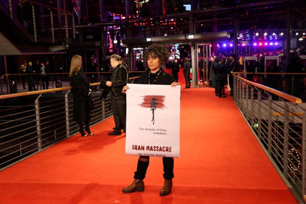February 12, 2026, Berlin, Germany: A woman with the poster Iran Massacre poses on the red carpet at the opening ceremony of the 76th Berlin International Film Festival (Berlinale), which is Europe s first major film festival of the year, in Berlin. The festival runs from February 12 to 22, 2026. Berlin Germany  - ZUMAf146 20260212_zip_f146_218 Copyright: xRouzbehxFouladix