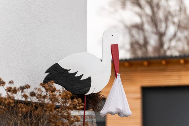 Ein Storch aus Holz mit einem Tuch im Schnabel, steht vor dem Haus einer Familie, die ein Baby bekommen haben. In vielen Regionen Deutschlands ist es noch immer ein gängiger Brauch, zur Geburt eines Babys einen hölzernen Storch im Garten oder auf dem Dach des Hauses der frischgebackenen Eltern aufzustellen. Rottweil Baden-Württemberg Deutschland *** A wooden stork with a cloth in its beak stands in front of the house of a family who have had a baby In many regions of Germany, it is still a common custom to place a wooden stork in the garden or on the roof of the new parents house to mark the birth of a baby Rottweil Baden Württemberg Germany