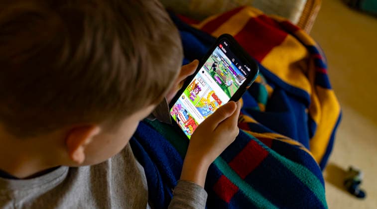 13.02.2026, Deutschland, ein 8-jähriges Kind sieht sich auf einem Handy über YouTube die Anleitung für die Bedienung der Online-Spieleplattform Roblox an *** 13 02 2026, Germany, an 8-year-old child watches the instructions for operating the online gaming platform Roblox on a cell phone via YouTube