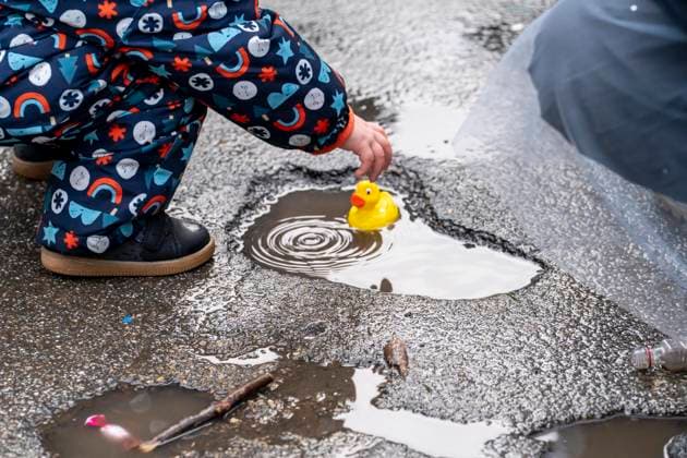 Rosenmontagszug in Düsseldorf, Teilnehmer des Umzugs, Kind spielt mit Plastikentchen, das es beim Zug als Kamelle gefangen hat, machen sich regenfest, beim Strassenkarneval, bei teils starkem Regen, NRW, Deutschland Rosenmontag DUS *** Rose Monday parade in Düsseldorf, participants in the parade, child playing with plastic ducklings it caught as camels during the parade, getting ready for the rain, at the street carnival, in heavy rain, NRW, Germany Rose Monday DUS